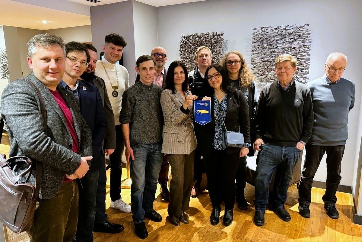 Wspólne zdjęcie członków dwóch klubów; pośrodku dwie osoby trzymają proporczyk Rotary Club Warszawa-Żoliborz