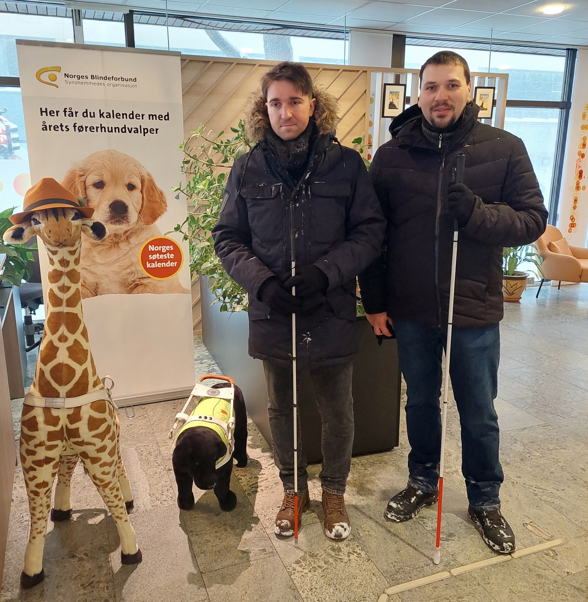 Dwaj mężczyźni z białymi laskami przed rollupem Norges Blindeforbund