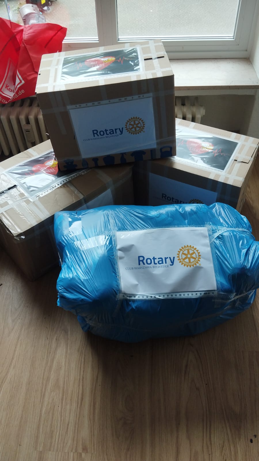 Kartony i zawinięta w folię paczka z naklejkami Rotary Club Warszawa-Belweder, przygotowane do wysyłki